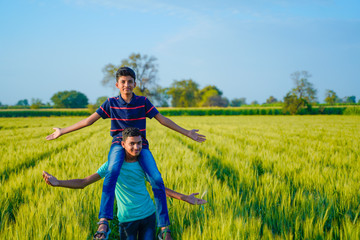 Brother piggyback his little brother in wheat field, rural india