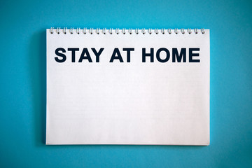 STAY AT HOME text on a notepad on a blue background