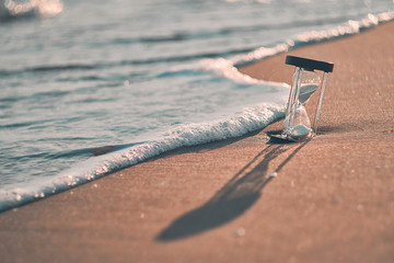 Hourglass at beach coast as time passing concept for business deadline, urgency and running out of...