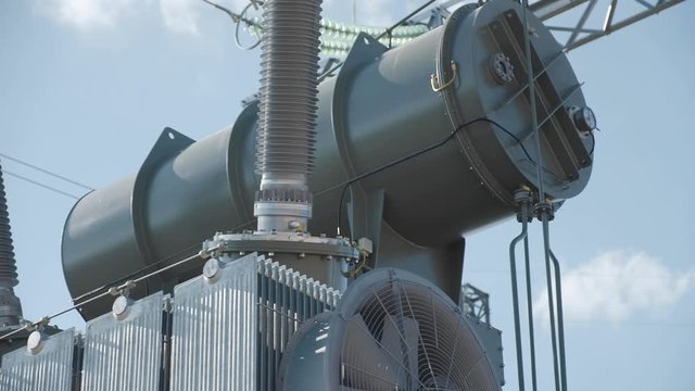 high voltage electric transformer on the background of insulators, metal structures and blue sky