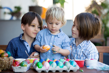 Fototapeta premium Sweet children, brothers, coloring and paiting eggs for Easter in garden, outdoor at home in backyard