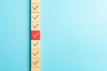 Checklist concept, Check mark on wooden blocks, blue background with copy space