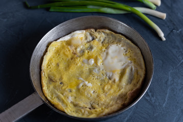 omelet in a pan and green onions for breakfast