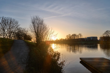 A beautiful sunrise with winter plants and a small jetty in the foreground overlooking a German lake 