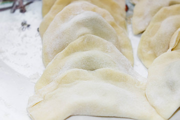 Molded raw dumplings lie on the table in a row before cooking.