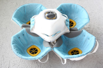 Respirators lie on a gray concrete surface. The concept of protecting the lungs from dust and...