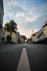 Low road view of a German street with tram tracks and vibrant houses on each side during sunset