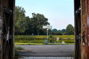 View of scenic green German river seen through large flood gates with a directions sign as the focal point