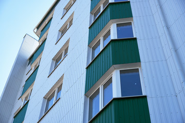 facade of a new multi-storey building with white and green metal siding, many Windows