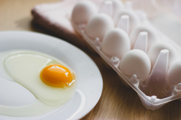 eggs in package and yolk on a white plate on the table