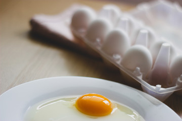 eggs in package and yolk on a white plate on the table