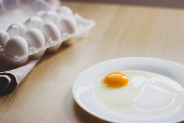 eggs in package and yolk on a white plate on the table