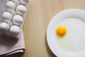 eggs in package and yolk on a white plate on the table