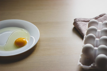 eggs in package and yolk on a white plate on the table