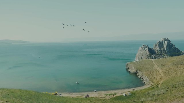 Aerial View of the Baikal Bay Shamanka. White ship in calm bay at great lake. Olkhon Island, Baikal, Russia, Siberia. Drone footage. UNESCO World Heritage Site
