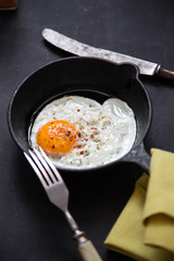 Egg in a frying pan on a black background