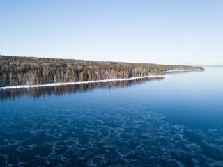 Fototapeta premium Aerial view on the Onega lake covered with thin ice and the forest, northwest of Russia