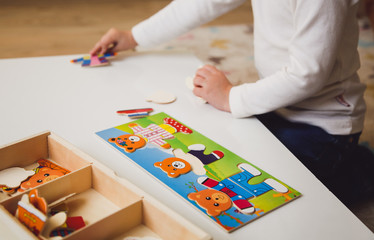 Child's hands with colorful board game on the white table. Child playing at the table. Early development of a child concept. Early development of a child concept. 