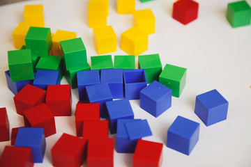 Child's hands with colorful cubes on the white table. Child playing at the table. Early development of a child concept. 
