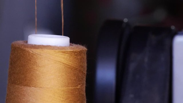 Close up of a spool of thread on sewing machine, yarn unwinds. 