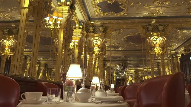 Luxury restaurant in a five-star hotel golden decoration and big mirrors around. The camera is moving backwards while zooming in so that it creates a dolly zoom effect.