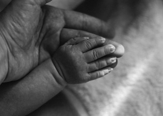 The baby's tiny hand is resting on the mother's arm. Black and white photo.