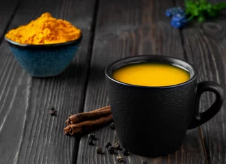 Fotobehang Cup with natural healthy herbal tea made from turmeric, honey and spices. Drink to support immunity against influenza and the common cold. The concept of medicine and a healthy lifestyle. Close-up © Ed