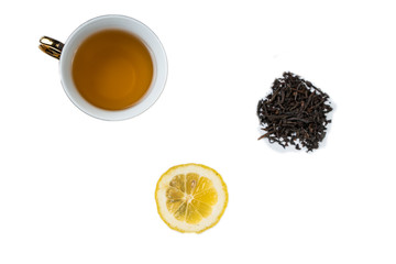 A cup of tea, dried tea grass and sliced lemon on a white background
