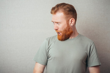  Profile of Young hipster red bearded Man standing against grey background
