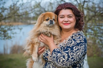 Woman with a  dog is a human best friend. Pekingese light red color resting with his owner enjoying...