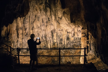 Silhouette of a man taking pictures in a cave with smartphone.