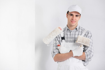 Painter in overalls holding a brush and roller - 339116004