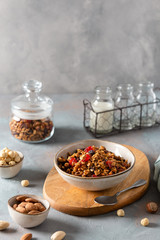 Healthy breakfast granola, muesli with berries, nuts and honey in a bowl on gray concrete background. Copy space, side view