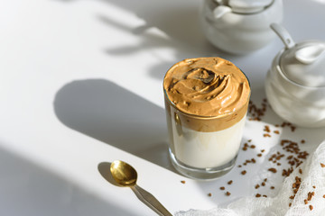 trendy dalgona coffee in glass with shadow on white background, iced coffee, whipped coffee, korean coffee concept