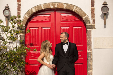 Happy wedding couple posing in front of big red door