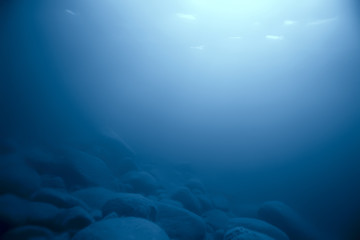 Fototapeta na wymiar stones at the bottom underwater landscape, abstract blurred under water background