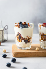 Crunchy honey granola with yogurt in a glass on gray background. Dry breakfast cereals with flax...
