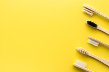 Zero waste concept. Set of eco friendly bamboo toothbrushes on a bright yellow background. Flat lay, copy space, horizontal orientation. Layout natural organic hygiene products.
