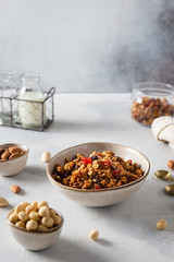 Healthy Breakfast. Muesli with blueberries, almonds, raisins, hazelnuts, honey and yogurt in glasses on a white concrete background. Side view, copy space. Recipe