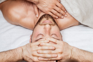 Man receiving relaxing head massage by massage therapist hands, top view.
