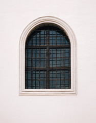 Antique old window with iron bars framed on a gray wall. The Jesuit Church in Lviv.