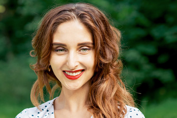 Portrait of beautiful young smiling woman on green summer nature background.