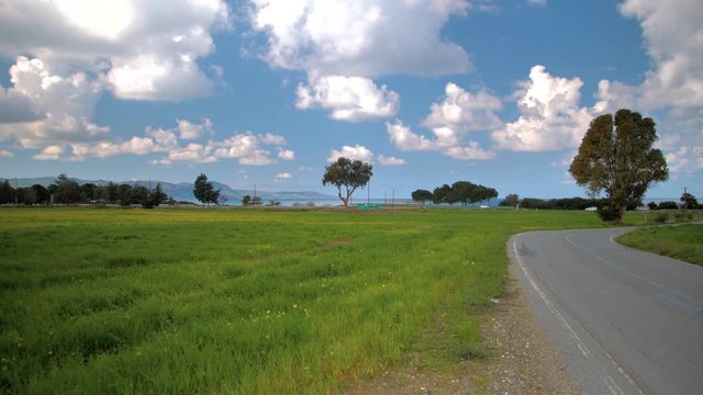 A road with cars going through the green, open landscape of Cyprus - wide shot