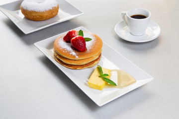 Donut and pancakes with strawberries on white table