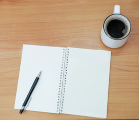 Top view of cup of coffee and notebook with pen.