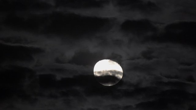 Beautiful full moon crossing the sky, clouds passing in front