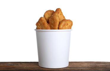 Bucket with tasty chicken nuggets on wooden table against white background
