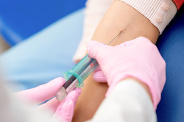 Obraz na płótnie Canvas Nurse introducing the coronavirus vaccine introducing a needle into a vein of arm of woman.