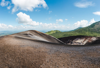 Scenic view over a volcanic crater and lush green mountains around Cerro Negro, an active volcano...