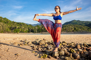 Asian Thai woman practicing yoga at evening in Mae Haad beach, Koh Phangan island, Thailand.